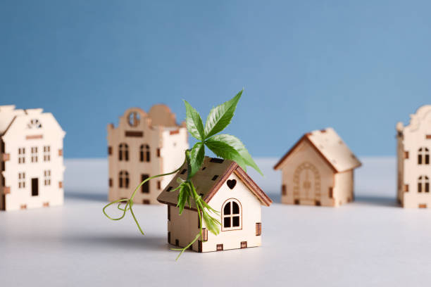 retrofit movement, future proofing homes, net zero carbon, adapting buildings concept. toy houses with green leaf on roof on blue background.