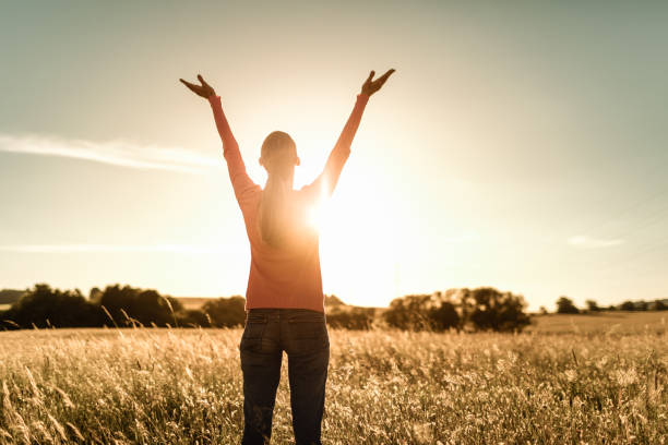 manos levantadas hacia el cielo del amanecer tocando los cálidos rayos del sol. - arms lifted fotografías e imágenes de stock