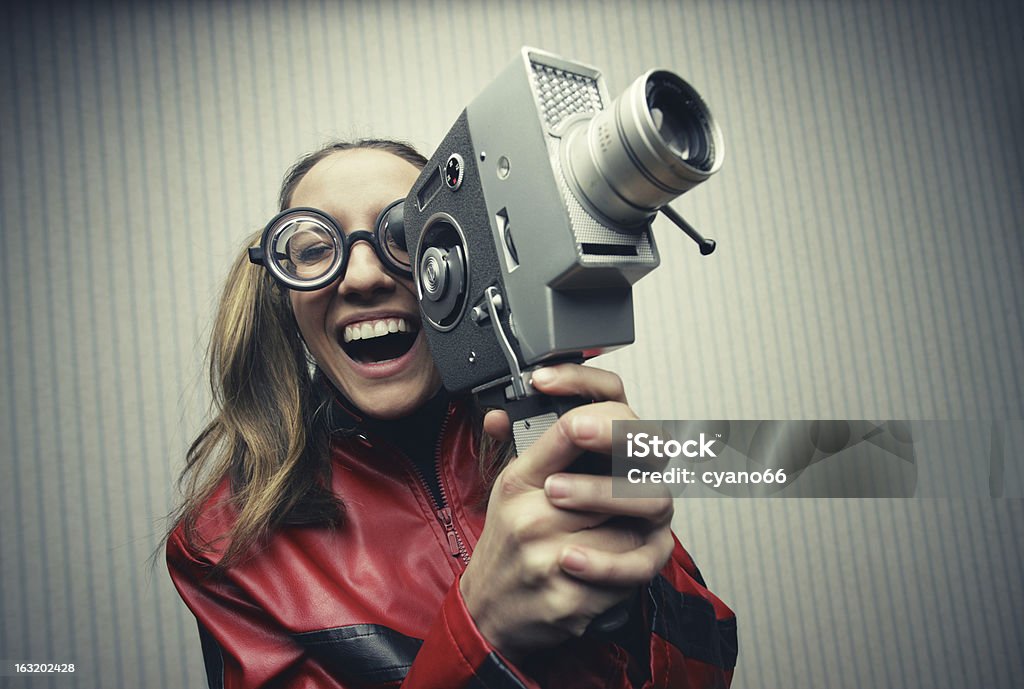 Laughing woman filming movie with vintage video camera Nerdy woman using old fashioned cine camera Film Director Stock Photo