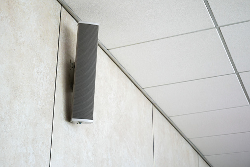 White loudspeaker in the conference room on the wall under the ceiling
