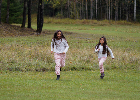 two siblings running outdoors in field