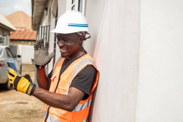 istock a man in safety gear with hammer next to building site 1632075835