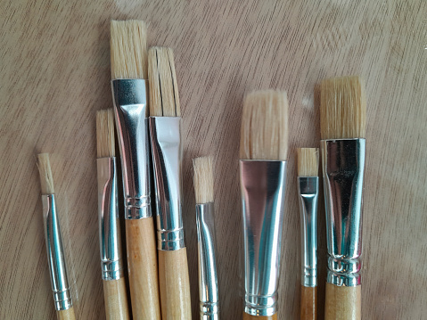 Row of artist paintbrushes closeup on wooden background