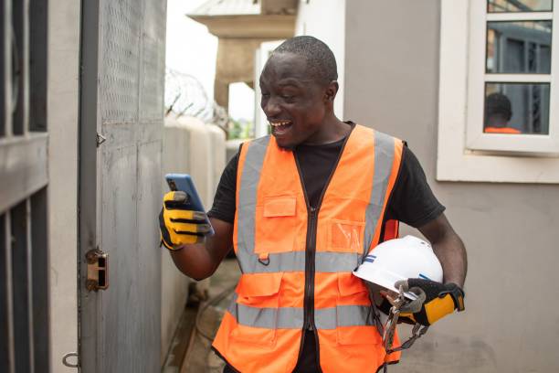 istock Man stands with a cordless device in hand next to a residential dwelling 1632077494