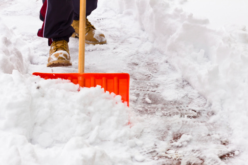 Close-up of shovel as man clears snow  from path