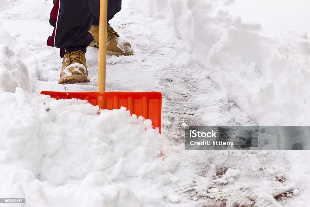 Snow Shoveling Close-up of shovel as man clears snow  from path Snow Stock Photo