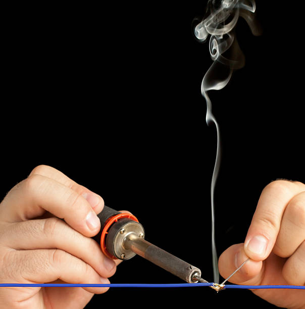 istock Technician soldering two wires together on a black background. 163211092