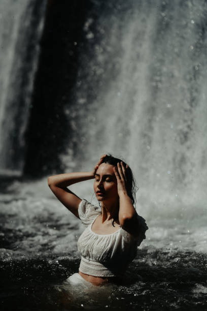 istock Beautiful Female Closing Her Eyes While Submerging Herself In Waterfall Pool 1632111303