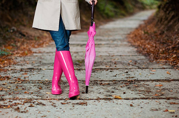 istock Woman walking down a sidewalk with a pink umbrella and boots 163213647
