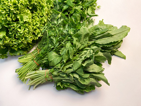 Fresh organic lettuce, arugula, parsley, mint leaves, cress and dill on white background. Fresh organic green leaf vegetables