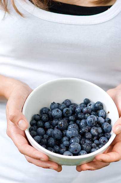 istock Young woman holding bowl filled blueberries 163216136
