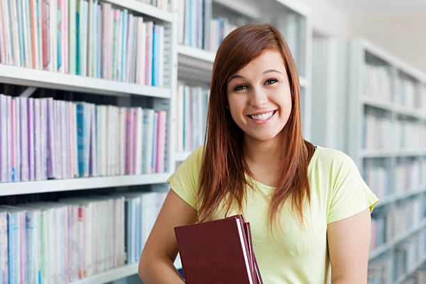 istock Cheerful student girl holding books in library 163216241