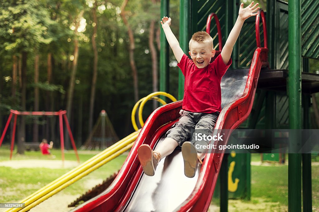 Active boy sliding down Slide - Play Equipment Stock Photo