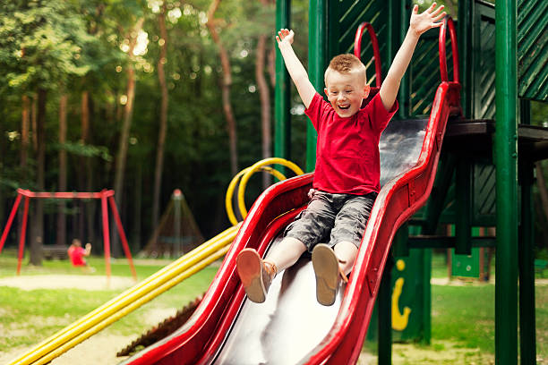 активный boy sliding вниз - schoolyard playground playful playing стоковые фото и изображения