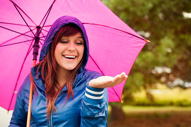 istock Cheerful woman under pink umbrella checking for rain 163216470