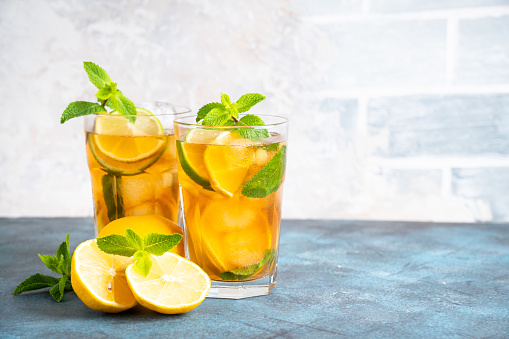 Iced tea. Black tea with lemon, lime, mint and ice. Cold lemonade, summer drink at kitchen table.