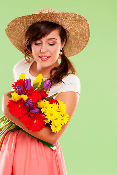 istock Woman wearing straw hat holding spring flower 163218612