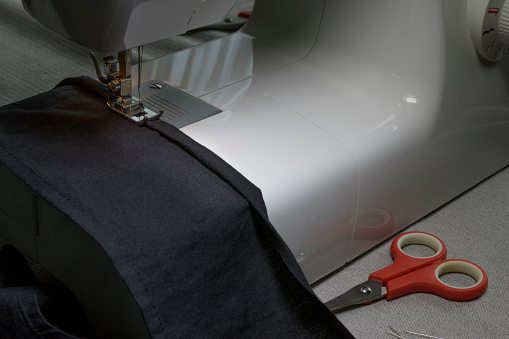 Woman tailor at work on sewing machine.