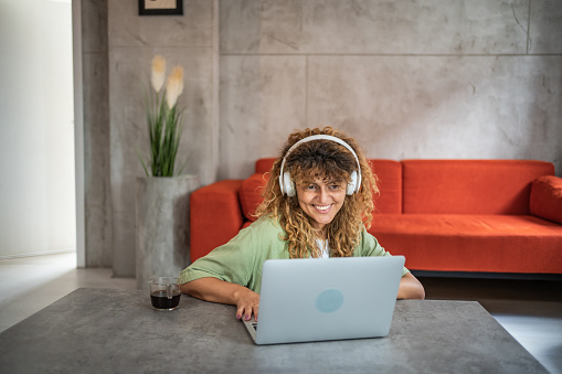 The photo shows a moment of relaxation, personal satisfaction and comfort as a young woman watches an online movie on her laptop at home