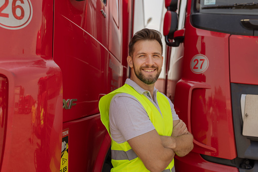 Portrait of Confident Truck Driver With Arms Crossed on Parking Lot Looking at Camera