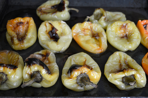 oven baked bell pepper on a black baking sheet. snack ingredient. cooking peppers before serving with tomato sauce, garlic and fragrant herbs. dinner at home