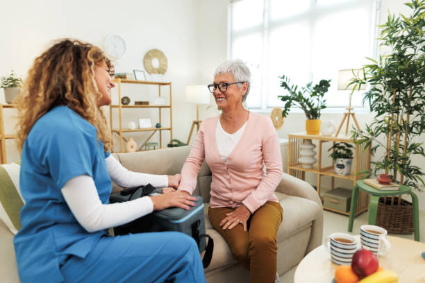 Smiling senior woman talking with nurse at home during visit