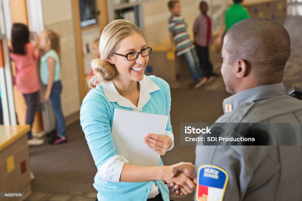 Friendly school teacher welcoming police officer for safety speech Friendly school teacher welcoming police officer for safety speech. Police Force Stock Photo