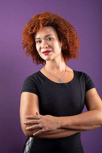 an attractive red-haired woman posing for a photo in black clothing. Confident and happy. Isolated on lilac colored background.