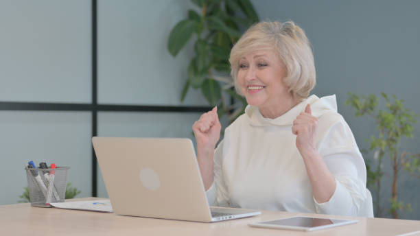 istock Old Woman Celebrating Success on Laptop 1632289623