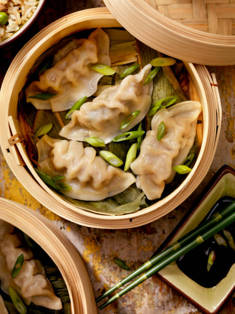 Steamed Dumplings Steamed Dumplings in a bamboo steamer with bamboo leaves, fresh green onions, soya sauce and rice -Photographed on Hasselblad H1-22mb Camera dumpling stock pictures, royalty-free photos & images