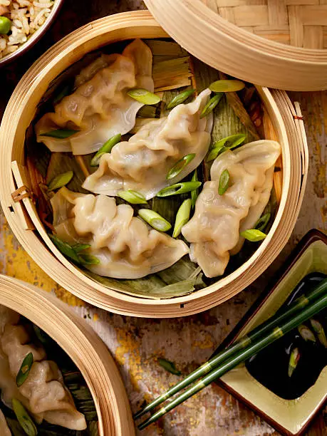 Steamed Dumplings in a bamboo steamer with bamboo leaves, fresh green onions, soya sauce and rice -Photographed on Hasselblad H1-22mb Camera