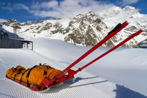 Empty mountain rescue sled over snow on mountain