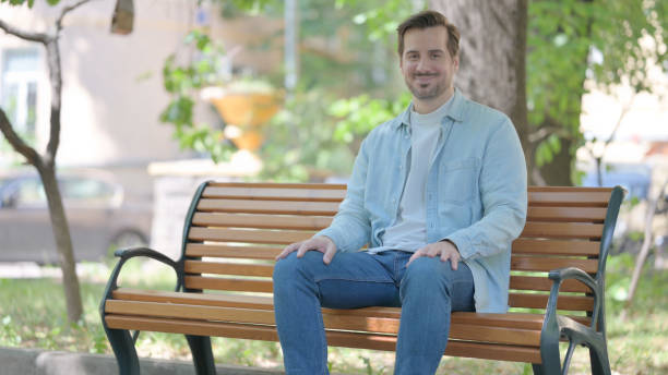 istock Smiling Young Man Sitting Outdoor and Looking at Camera 1632351498