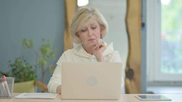 istock Senior Old Woman Thinking and Working on Laptop 1632388198