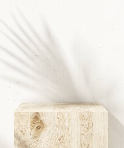 istock Cube wooden table podium with beautiful wood grain in sunlight with palm leaf shadow on white wall 1632393324
