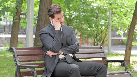 Sleeping Young Businessman Sitting Outdoor on Bench