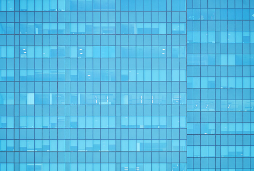 A close-up view of a modern office building in Gothenburg, Sweden, showcasing a symmetrical pattern of windows that reflect the blue sky. The golden hues of the buildings exterior panels contrast with the reflected azure, demonstrating a blend of urban design and natural beauty.