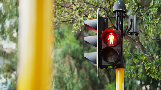 Red sign for walkers to stop on a traffic signal at the intersection of an crossroad