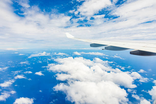 View from plane flying through clouds over the ocean on a sunny bright day.