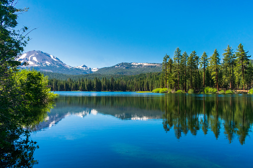 Lassen Peak reflects in beautiful Manzanita Lake in Lassen Volcanic National Park with blue sky