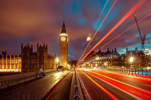 Iconic landmark and famous tourist attraction - Big Ben with light trails from cars and double decker bus at dusk.