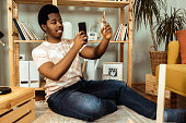 African American young man making a video call while doing some carpentry work at home