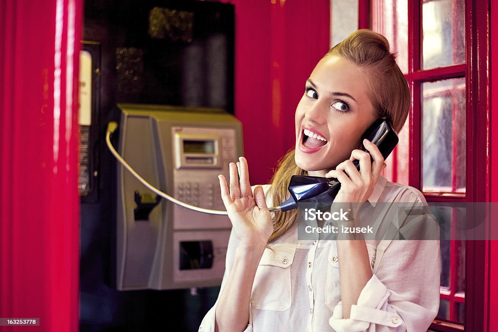 Hermosa mujer en una cabina de teléfono roja - Foto de stock de 20-24 años libre de derechos