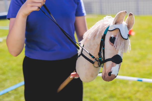 competición de afición en una hierba verde, jinetes aficionados a saltar, entrenamiento deportivo ecuestre con caballos de juguete de palo en un día soleado de verano, equipo para aficionar - caballo de juguete fotografías e imágenes de stock