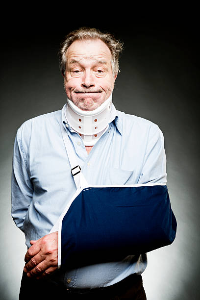Mature Man With Whiplash With Neck Brace and Sling Senior man suffering from whiplash and a broken arm maybe the result of a car accident. man with arm sling stock pictures, royalty-free photos & images