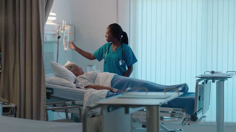 Hospital bed, senior patient and nurse talk with night check and healthcare monitor in ICU. Elderly, person and working on health, wellness and care for cancer and clinic consulting and nursing