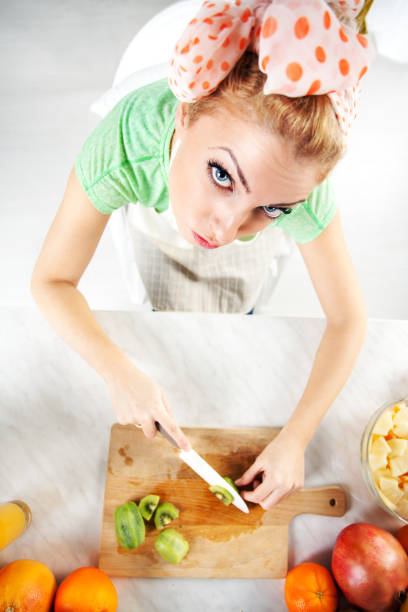 Young woman slicing kiwi