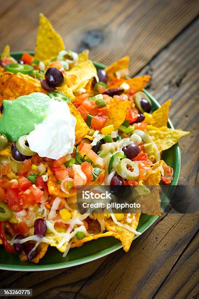 Fully Loaded Nachos In A Green Plate On A Wooden Table Stock Photo - Download Image Now