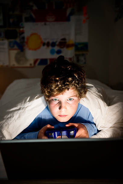 Late Night Not Ready For School Young boy 10 years old playing on his computer late at night. Illustrating the idea that children are too tired for school in the morning. Distracted stock pictures, royalty-free photos & images