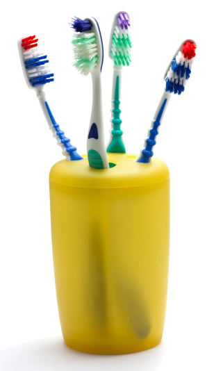 4 used Toothbrushes in a yellow toothbrush holder.